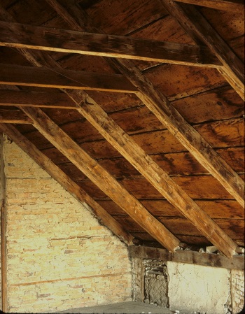 Fairfield House west attic with view of east partition wall of handmade bricks and of the hewn rafters supporting original pine roof boards.